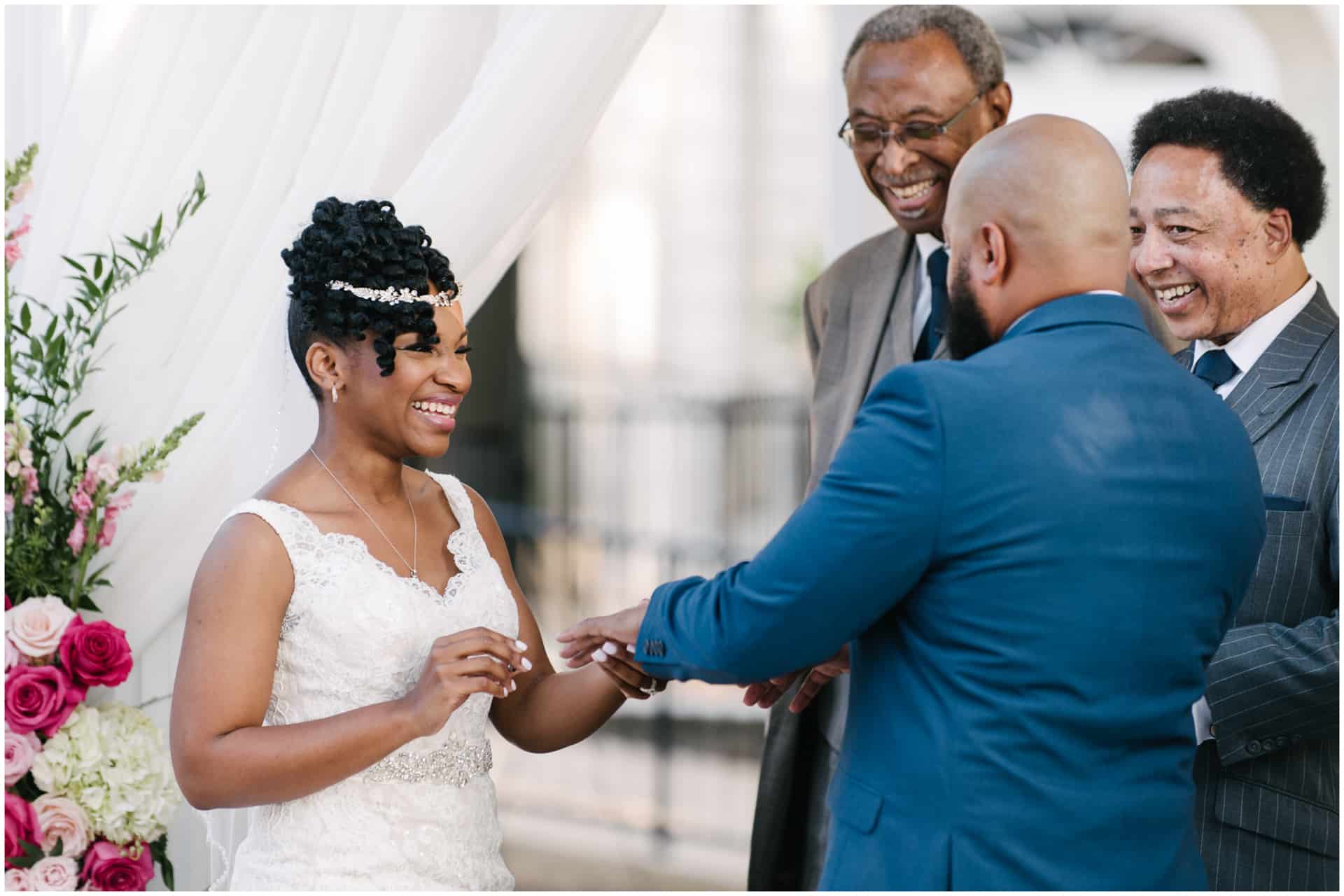 African American Bride put wedding band on groom All smiles