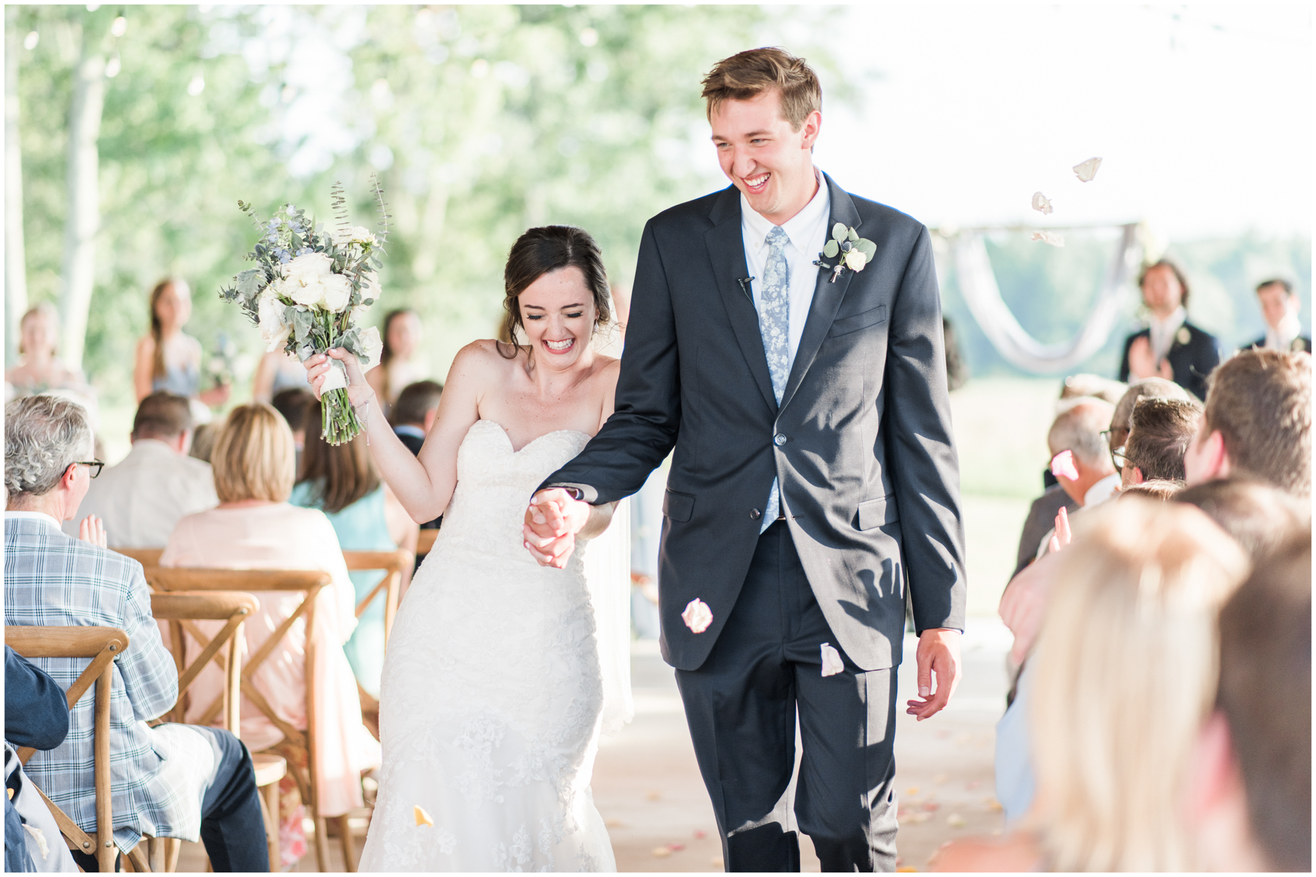 Outdoor Ceremony at Harvest Hollow - Guest tosses flower petals while bride and groom walk down the aisle
