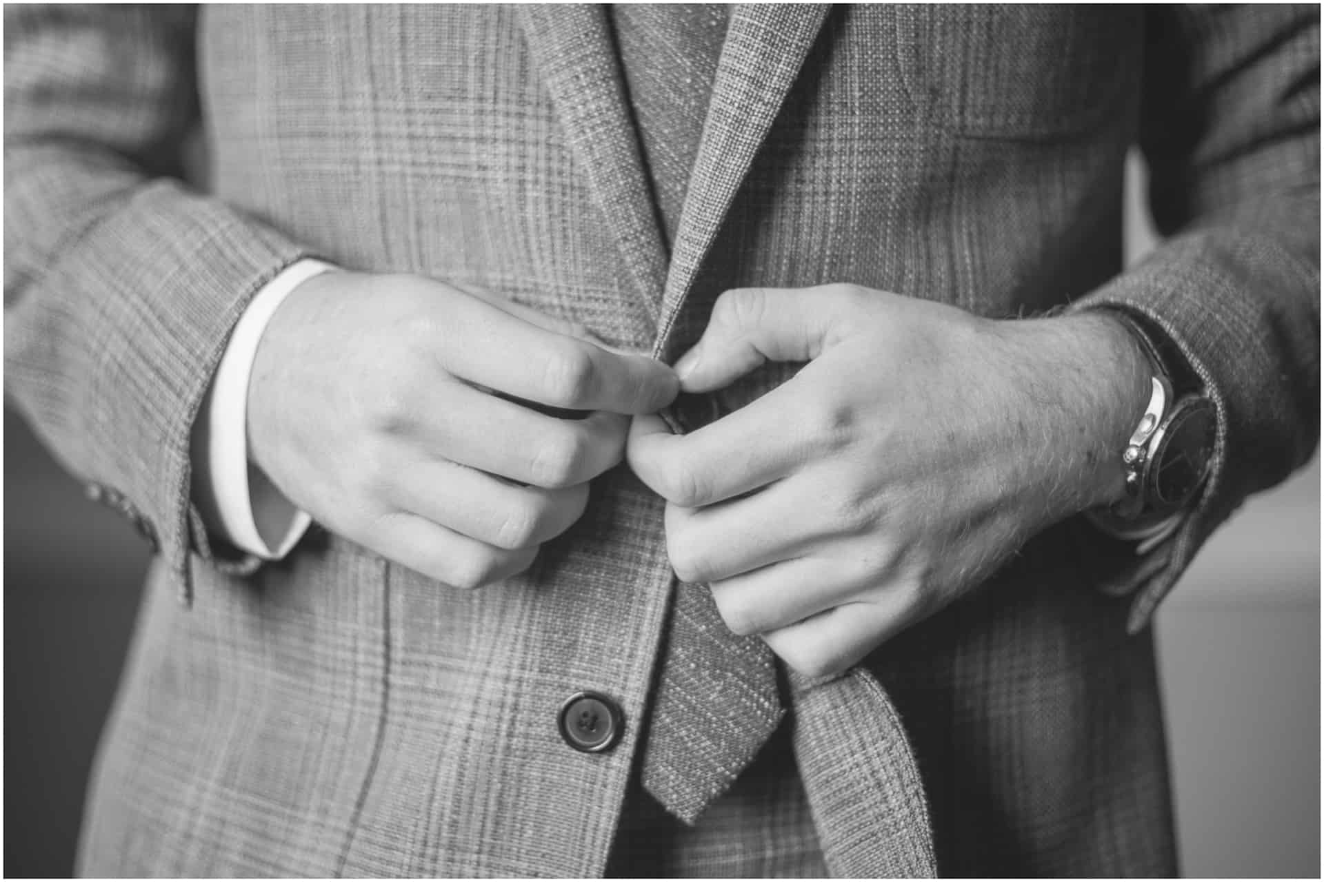 black and white of groom buttoning suit Huntsville Alabama 