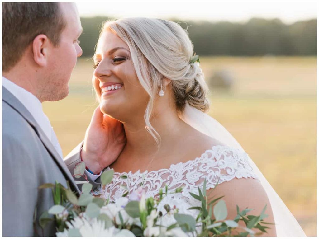Harvest Hollow Venue and Farm Golden Hour Portraits in a Field - Groom caressing brides face - bride laughing