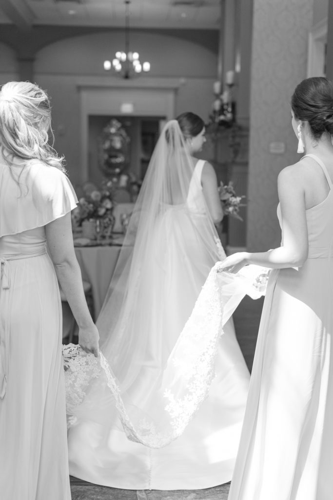 Bridemaids carrying brides veil black and white image