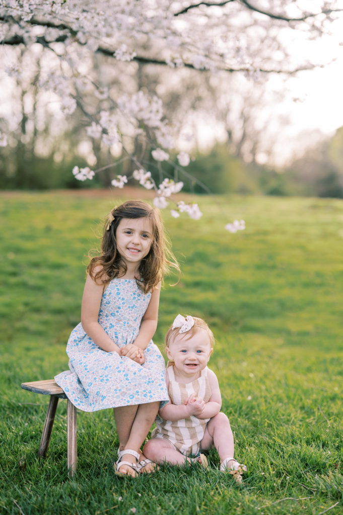 Two little girls sitting under a cherry blossom tree