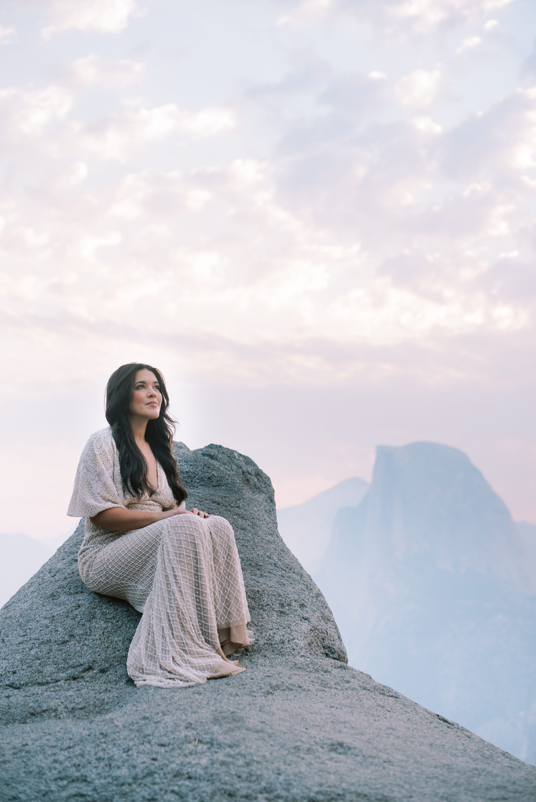 Bridal Session at Yosemite National Park - Bride sitting on a rock at Glacier Point with Half Dome in the background at sun rise


